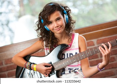 Portrait of cute teenager girl at guitar practice at home.