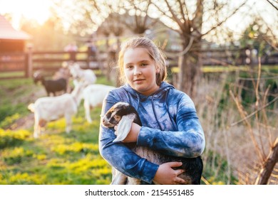 Portrait of cute teenager girl with holding goat kid domestic animal at farm in countryside. Agritourism concept. - Powered by Shutterstock