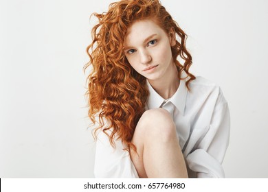 Portrait of cute tender ginger girl with curly hair looking at camera over white background.