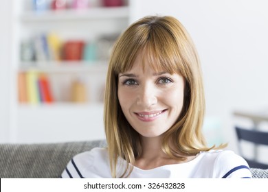 Portrait Of Cute Thirty Year Old  Woman In White Modern Apartment. Face Camera