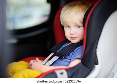 Portrait of cute toddler boy sitting in car seat. Child transportation safety

