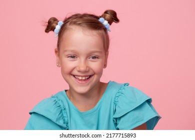 Portrait of cute toddler girl child with two funny tails over pink background. Advertising childrens products. Funny face