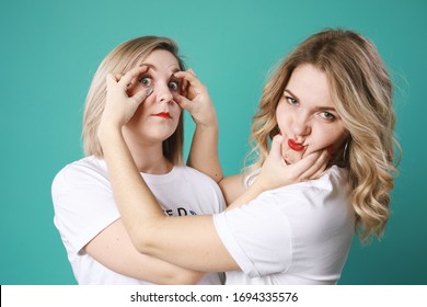 Portrait of cute twins blondes grimace each other isolated on green background