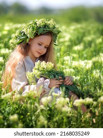 Portrait Of A Cute Village Girl Kid In A Wreath On A Flower Field.. A Child In A Blooming Meadow.