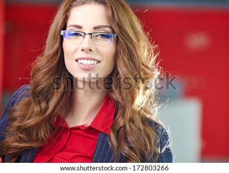 Portrait of a cute young business woman smiling, in an office environment 