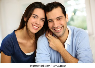 Portrait Of Cute Young Couple Sitting In Sofa