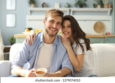 Portrait Of Cute Young Couple Sitting In Sofa.