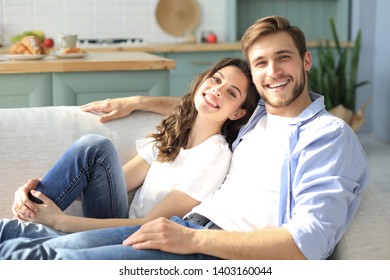 Portrait Of Cute Young Couple Sitting In Sofa.