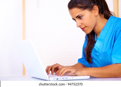 Portrait of a cute young nurse using a laptop.