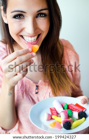 Portrait of Cute young woman eating jelly candies with a fresh smile