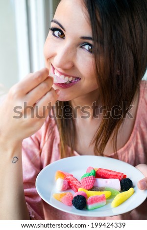 Portrait of Cute young woman eating jelly candies with a fresh smile