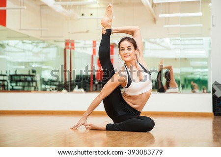 Portrait of a cute young woman stretching and practicing some gymnastic moves at the gym
