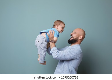 Portrait Of Dad And His Little Son On Color Background