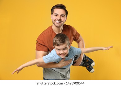 Portrait Of Dad Playing With His Son On Color Background