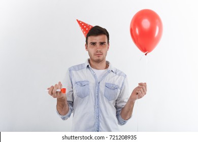 Portrait Of Dark Haired Unshaven Young Male Wearing Denim Shirt And Cone Hat Feeling Displeased Or Confused About Surprise Party Thrown By His Girlfriend. Human Emotions, Feelings And Reaction