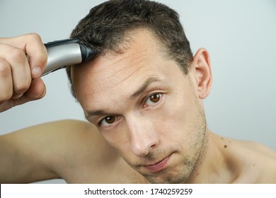 Portrait Of A Dark-haired Man Holding An Electric Razor On His Head, About To Shave Off His Hair.