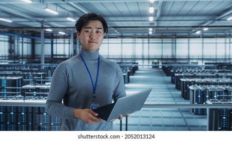 Portrait Of A Data Center Engineer Using Laptop Computer. Server Room Specialist Facility With Korean Male System Administrator Working With Data Protection Network For Cyber Security.