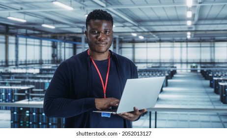 Portrait of a Data Center Engineer Using Laptop Computer. Server Room Specialist Facility with African American Male System Administrator Working with Data Protection Network for Cyber Security. - Powered by Shutterstock