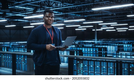 Portrait of a Data Center Engineer Using Laptop Computer. Server Room Specialist Facility with African American Male System Administrator Working with Data Protection Network for Cyber Security. - Powered by Shutterstock