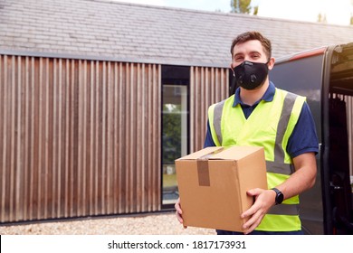 Portrait Of Delivery Driver Wearing Mask Holding Package Outside House