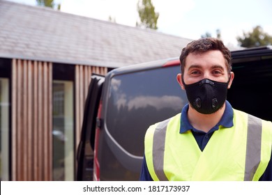 Portrait Of Delivery Driver Wearing Mask Next To Van Outside House