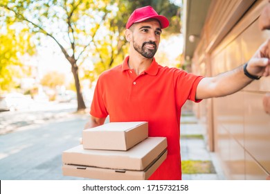 Portrait Of A Delivery Man With Cardboard Pizza Box Ringing House Doorbell. Delivery And Shipping Service Concept.