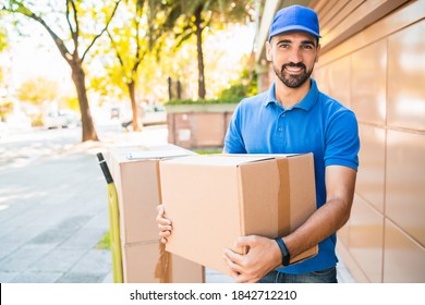 Portrait of a delivery man courier with cardboard boxes in hands outdoors. Delivery and shipping concept.