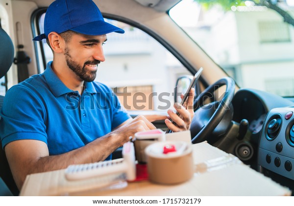 Portrait of a\
delivery man driver using digital tablet while sitting in van.\
Delivery service and shipping\
concept.