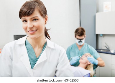 Portrait of a dental assistant smiling with dentistry work in the background - Powered by Shutterstock