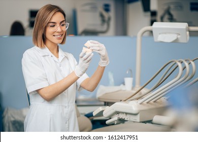 portrait of dental specialist at work, wearing white doctor's uniform, using medical instruments and equipment. Healthcare concept - Shutterstock ID 1612417951