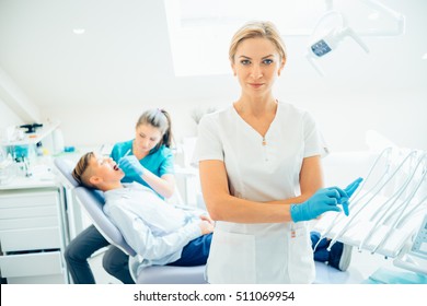 A Portrait Of A Dentist With His Team Working In The Background