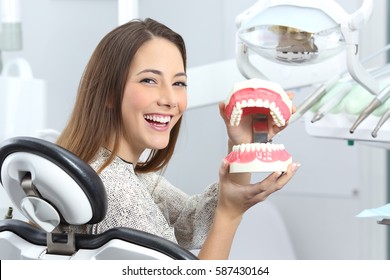 Portrait of a dentist patient smiling with perfect teeth after whitening treatment and holding a plastic denture in a box