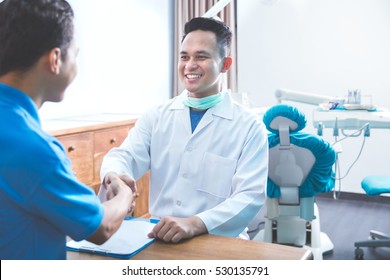 Portrait Of Dentist Talking To His Patient At Dental Care Clinic And Shaking Hands