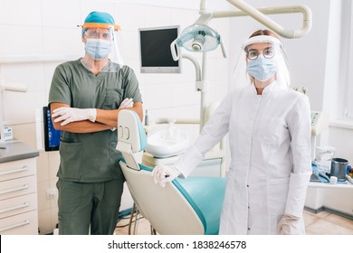 Portrait of dentist with young female assistant in full protective uniform at the dental office