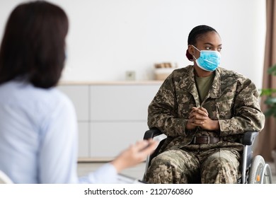 Portrait Of Depressed Black Military Woman In Wheelchair Having Therapy Session With Psychologist, Disabled African American Soldier Wearing Protective Face Mask Suffering Psychological Trauma