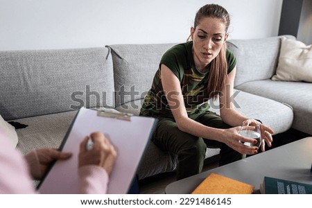 Portrait of depressed female soldier at home sitting on sofa.