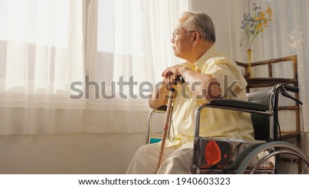 Portrait depressed lonely elderly man with wooden cane looking at windows, frustrated mature male folded hands on walking stick, sitting on wheelchair alone, loneliness and solitude, Care, Retirement.