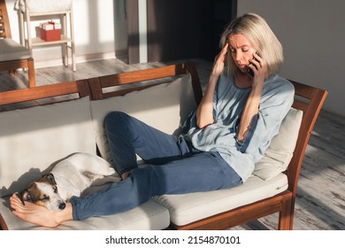 Portrait Of Depressed Middle Aged Woman Feel Upset And Sad After Phone Call, Bad News In Social Media Or Smart Phone Messenger Online App. Frustrated Beautiful Female Sit In Depression Alone On Sofa 