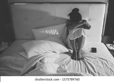 Portrait Of Depressed Woman Sitting Alone On The Bed In The Bedroom / Black And White Tone. Conceptual Of Bad Condition Of Broken Hearted, Sadness, Loneliness Or Depress Woman.