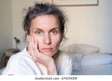 Portrait of despondent middle aged woman in bedroom (selective focus)