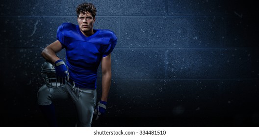 Portrait of determined American football player with hand on helmet against dark grey room - Powered by Shutterstock