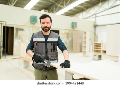 Portrait Of A Determined Handsome Male Worker Standing In A Woodshop And Holding A Chisel To Carve A Wood Table 