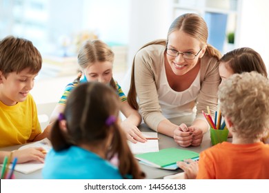 Portrait of diligent schoolkids and their teacher talking at lesson