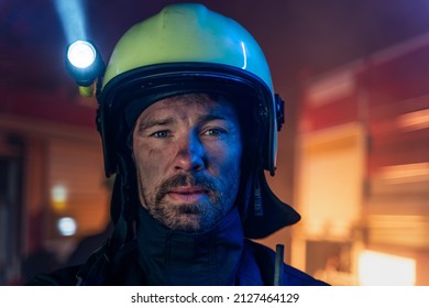 Portrait of dirty firefighter man on duty with fire truck in background at night, looking at camera. - Powered by Shutterstock