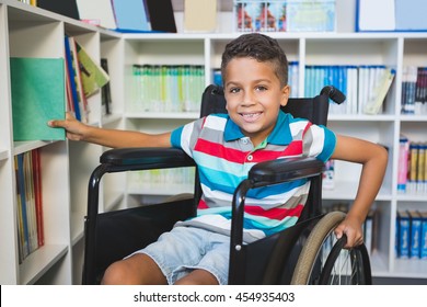 Portrait of disabled boy selecting a book from bookshelf in library at school