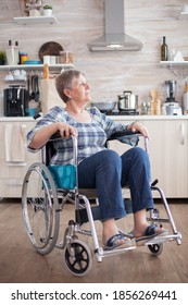 Portrait Of Disabled Unhappy Senior Woman In Wheelchair Looking Lost In Kitchen. Elderly Handicapped Pensioner After Injury And Rehab, Paralysis And Disability For Depressed Invalid Full Of Sorrow