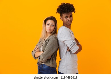 Portrait Of A Disappointed Multiethnic Couple Standing Isolated Over Yellow Background, Back To Back