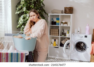 Portrait of a disappointed sad exhausted woman doing household chores since morning, cleaning, washing children's clothes and hanging them out to dry. - Shutterstock ID 2145176477