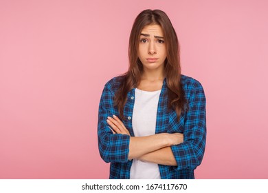Portrait of displeased unhappy brunette girl in bad mood looking at camera with resentful vexed face and holding hands crossed, worried about failure. indoor studio shot isolated on pink background