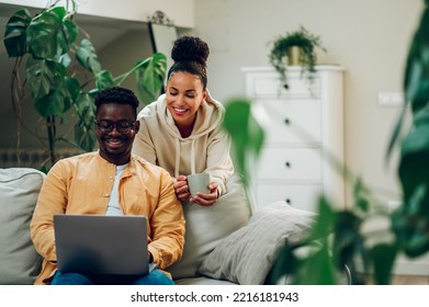 Portrait Of A Diverse Couple Enjoying Time At Home And Using Laptop. African American Man And Hispanic Woman Having Fun Together While Online Shopping Or Surfing Internet. Copy Space.